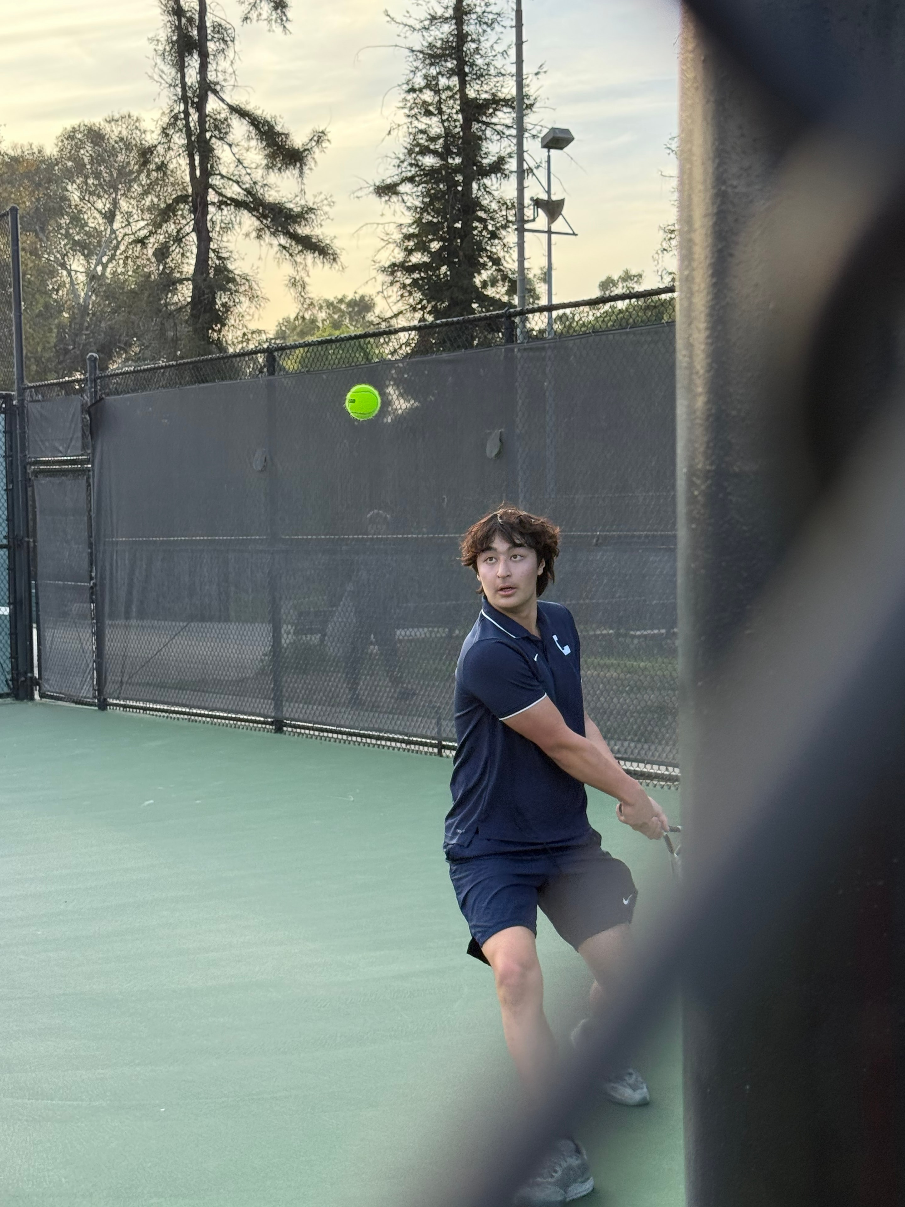 Teen boy playing tennis on court